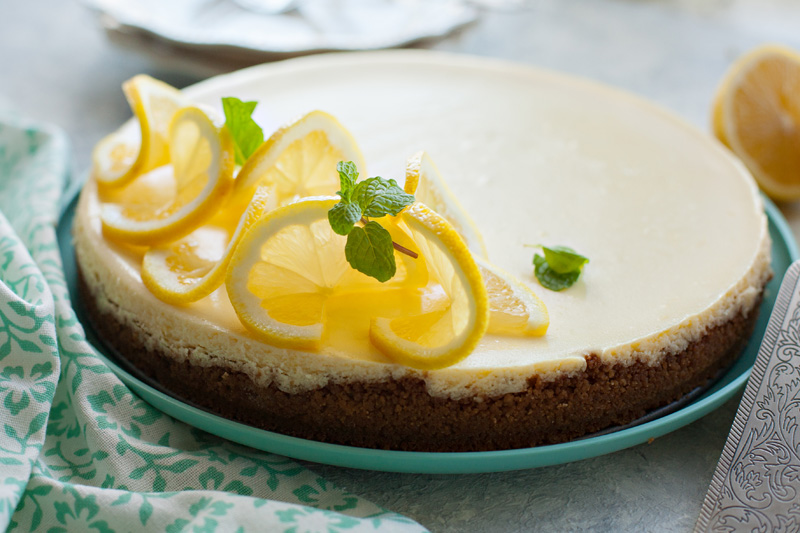 Classic Lemon Cheesecake with thinly sliced lemons and mint leaves