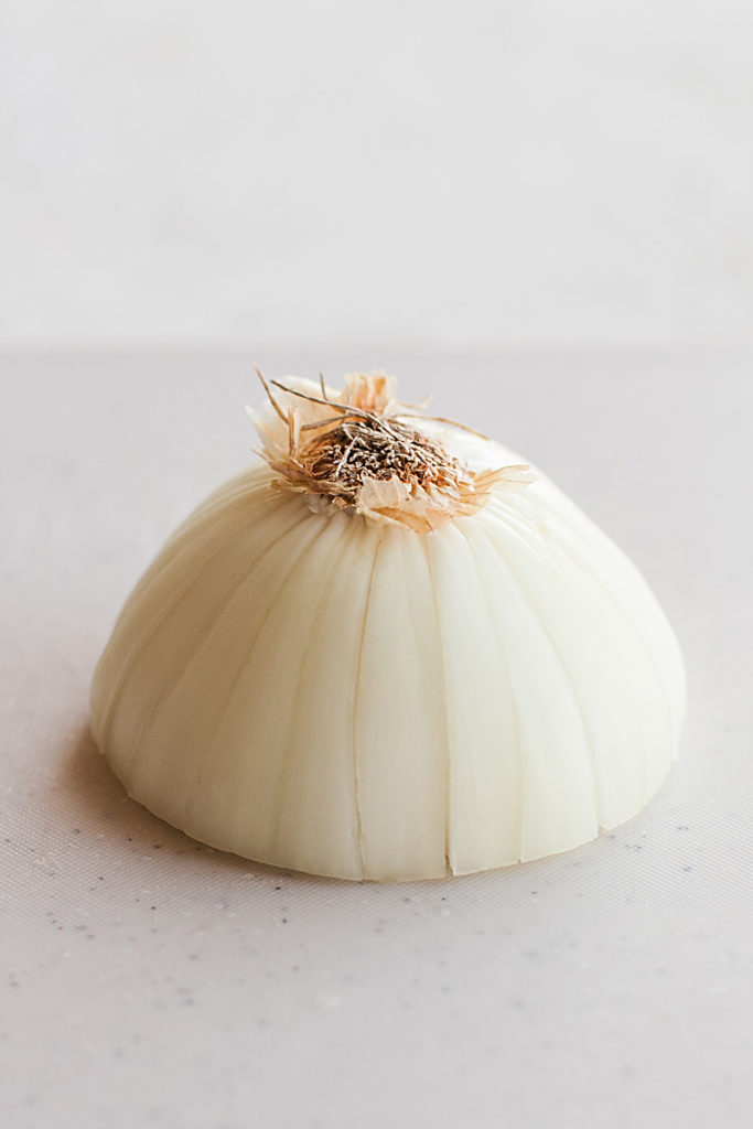 Half of a white onion sliced from the root to the center.