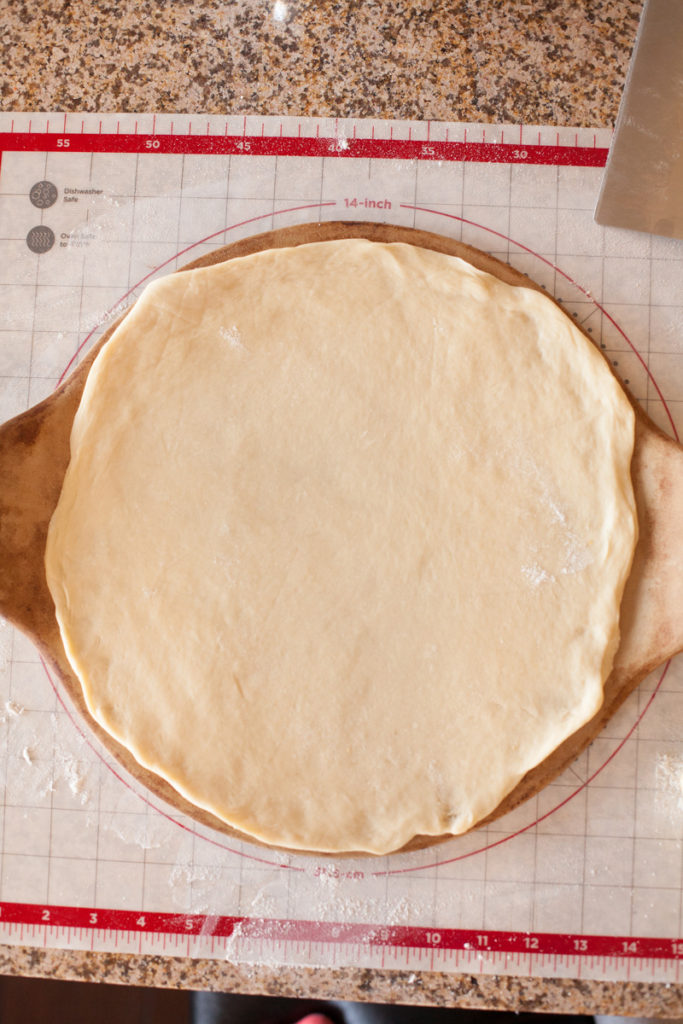 First layer of dough for Star Bread placed on top of a pizza stone.