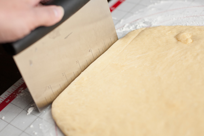 Maple bar dough being cut into a perfect rectangle.