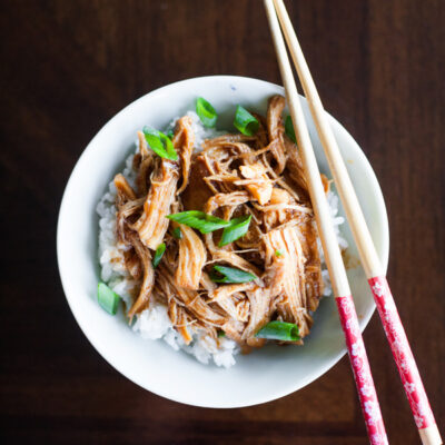 Sweet Chili Chicken on top of rice in a bowl with chopsticks.