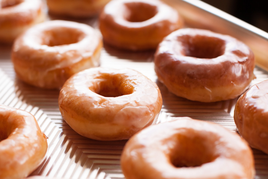 Homemade glazed donuts on metal cookie sheet.