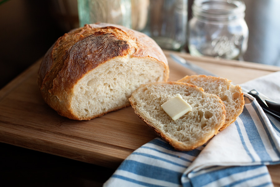 No-knead Dutch oven bread sliced with butter