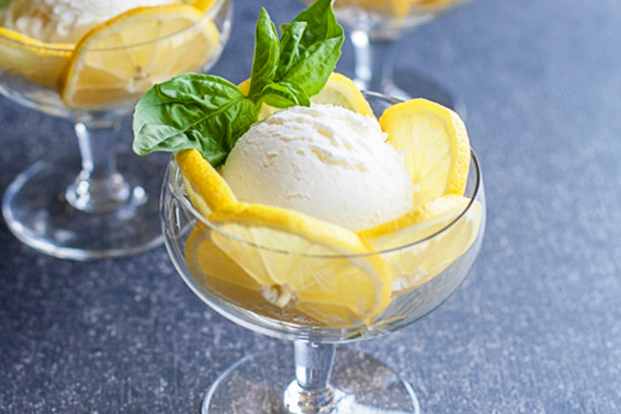 Fresh lemon ice cream in a glass serving cup with lemon slices and basil